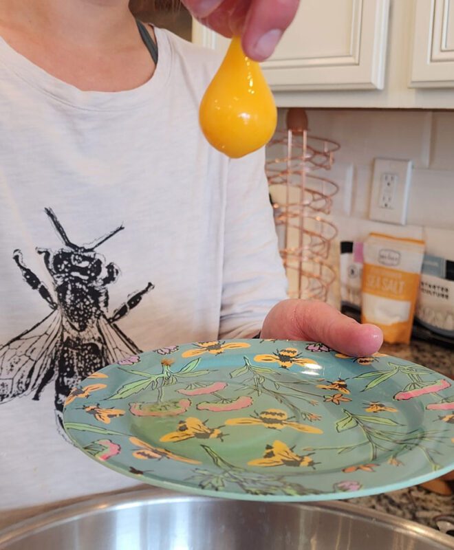 Lady holding yellow yoke of an egg.