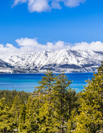 Aerial view of Lake-Tahoe on a sunny day with snow on the mountains.